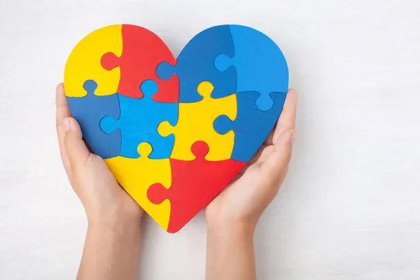 Światowy Dzień Autyzmu Świadomość, koncepcja zdrowia psychicznego z układanki lub układanki wzór na sercu z dłońmi dziecka — Zdjęcie stockowe