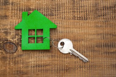 Evin ahşap zemin üzerinde gümüş anahtar simgesi