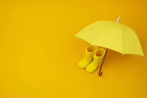 A pair of yellow rain boots and a umbrella on a yellow — Stock Photo, Image