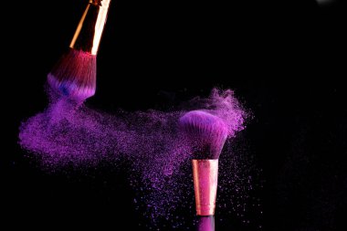 Makyaj fırça ile renkli toz patlama siyah arka plan üzerine su sıçramalarına