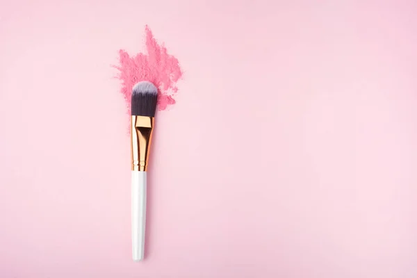 Brosse de maquillage sur fond rose avec de la poudre colorée de pigment. Vue du dessus — Photo