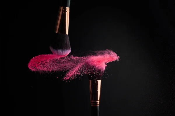 カラフルなパウダーで化粧筆跳ねる黒い背景に爆発 — ストック写真
