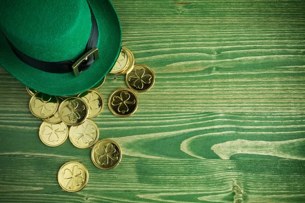 Happy St. Patricks Day leprechaun hat with gold coins on vintage green wood background — стоковое фото