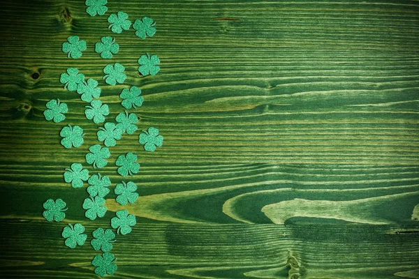 St Patricks Day side border of glitter paper shamrocks on green wood background — Stock Photo, Image