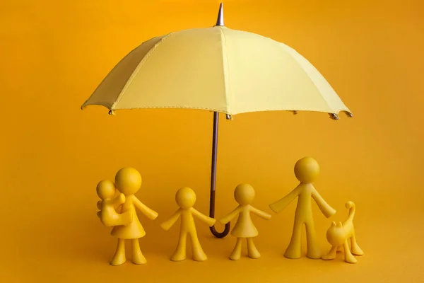 背景が黄色の傘と黄色い家族図 — ストック写真