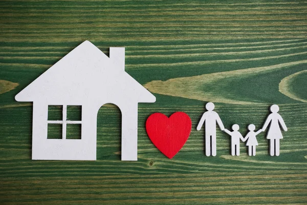 木製の緑の背景の家のある家族の図 — ストック写真