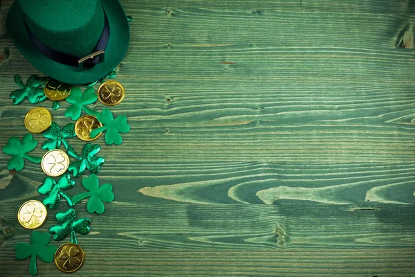 St patricks day frame aus Shamrocks, Goldmünzen und Koboldhut auf grünem Holz — Stockfoto