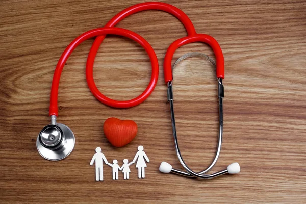 Concepto de Seguro Médico. Recorte familiar y estetoscopio sobre fondo de madera —  Fotos de Stock