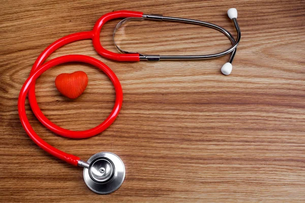 Stetoskop med rött hjärta på en trä bakgrund — Stockfoto