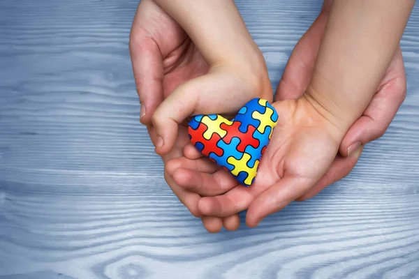 Día Mundial del Autismo Conciencia, rompecabezas o patrón de rompecabezas en el corazón con niños autistas y las manos del padre — Foto de Stock