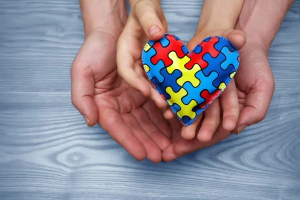 Día Mundial del Autismo Conciencia, rompecabezas o patrón de rompecabezas en el corazón con niños autistas y las manos del padre — Foto de Stock