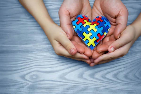 Mondo Autismo Consapevolezza giorno, puzzle o puzzle modello sul cuore con bambini autistici e le mani del padre — Foto Stock