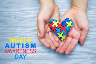 World Autism Awareness day, puzzle or jigsaw pattern on heart with autistic childs hands clipart