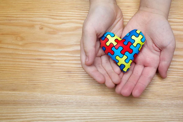 Svět autismus povědomí den, puzzle a skládačky vzorek na srdce rukama autistického dítěte — Stock fotografie