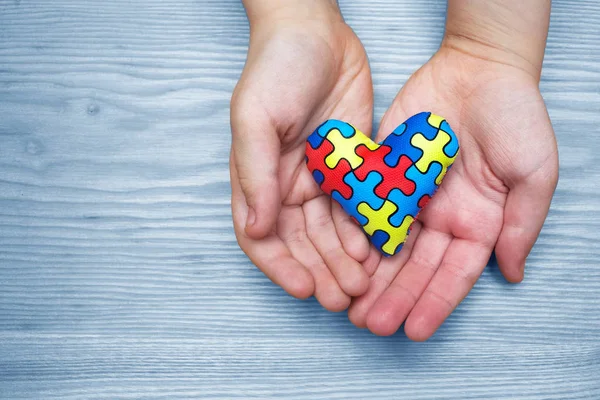 Día Mundial del Autismo Conciencia, rompecabezas o patrón de rompecabezas en el corazón con manos de niños autistas — Foto de Stock