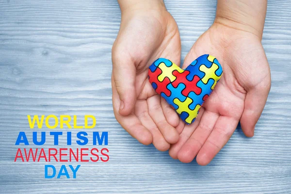 World Autism Awareness day, puzzle or jigsaw pattern on heart with autistic childs hands — Stock Photo, Image