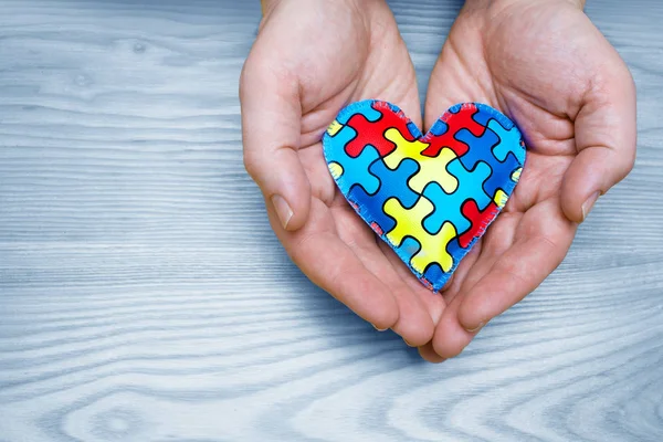 Ziua Mondială de Conștientizare a Autismului, puzzle sau model jigsaw pe inimă cu mâinile tatălui — Fotografie, imagine de stoc