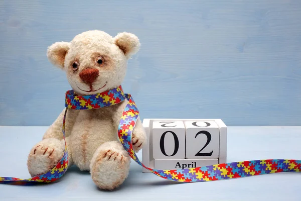 Всесвітній день аутизму, концепція з плюшевим ведмедем, що тримає пазл або візерунок головоломки на серці та календарі — стокове фото