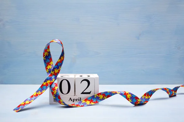 Världen Autism awareness och stolthet dagen med pussel mönster menyfliksområdet och kalender på blå trä bakgrund — Stockfoto