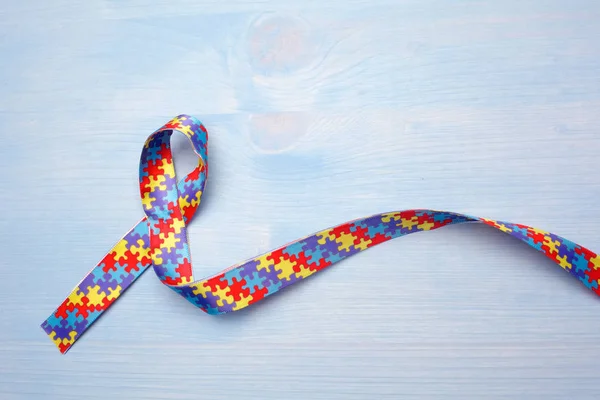 Världen Autism awareness och stolthet dagen med pussel mönster band på blå trä bakgrund — Stockfoto