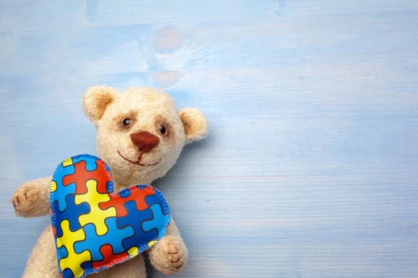 Autizmus Tudatosság Világnapja, koncepció játékmackó tartó puzzle vagy kirakós minta a szív — Stock Fotó
