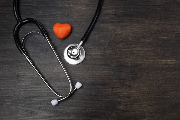 Concepto de salud. Estetoscopio cerca de la forma del corazón sobre fondo de madera oscura con espacio de copia —  Fotos de Stock