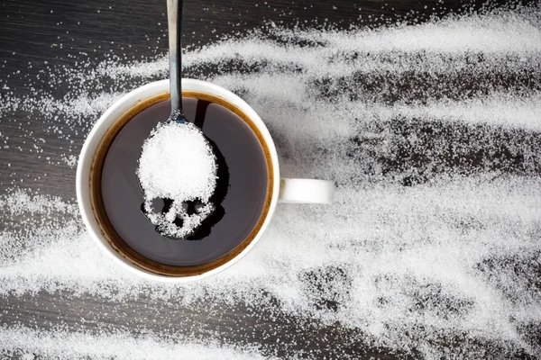 Conceito de açúcar branco não saudável. Colher Scull com açúcar e xícara de café preto em fundo de madeira — Fotografia de Stock