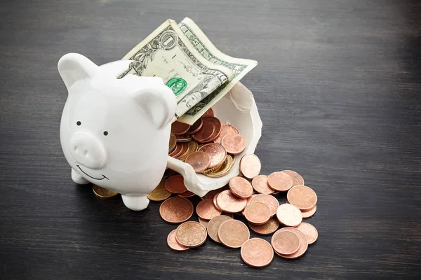 Broken piggy bank with money on dark wooden background — Stock Photo, Image