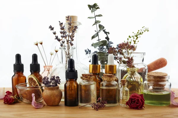 Aceites esenciales con hierbas y flores sobre mesa de madera — Foto de Stock