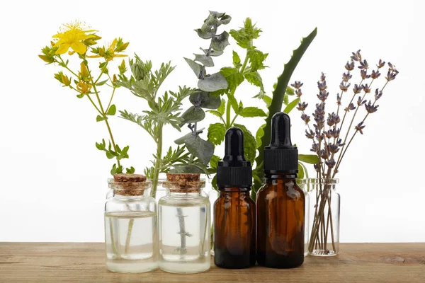 Aceites esenciales con hierbas y flores sobre mesa de madera — Foto de Stock