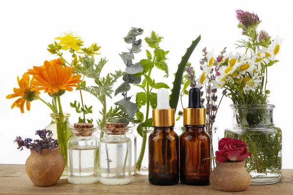 Aceites esenciales con hierbas y flores sobre mesa de madera — Foto de Stock