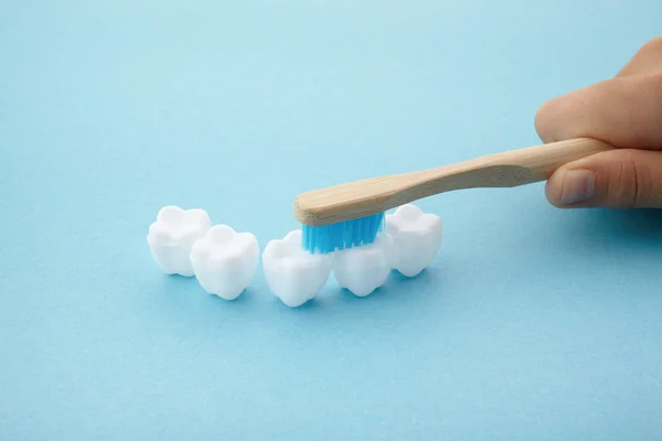 Mavi arka plan üzerinde diş fırçası ve beyaz platik diş ile çocuk el — Stok fotoğraf