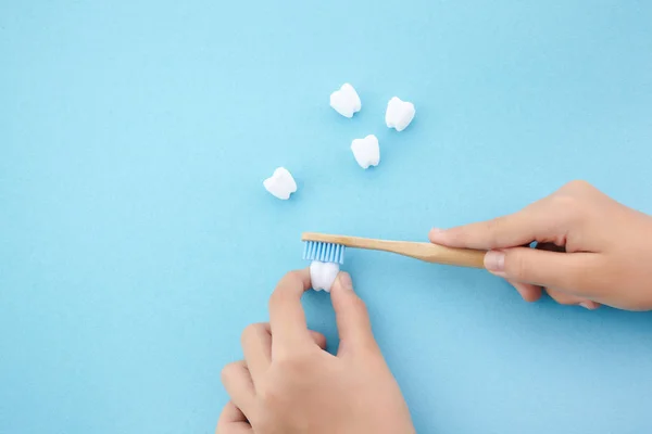 Childs hand met tandenborstel en witte platic tand op blauwe achtergrond — Stockfoto