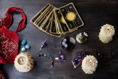 Tahta masanın üzerinde tarot kartları, sihirli taşlar ve mumlarla natürmort. Falcılık seansı veya sihirli ritüel.