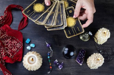 Falcı kadın elleri ve koyu ahşap masa üzerinde tarot kartları. Kehanet kavramı.