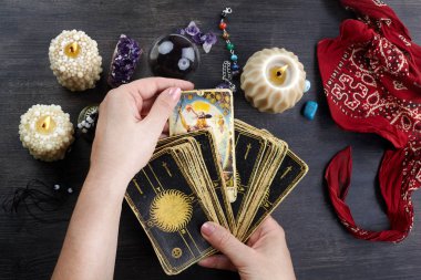 Falcı kadın elleri ve koyu ahşap masa üzerinde tarot kartları. Kehanet kavramı.