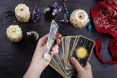 Falcı kadın elleri ve koyu ahşap masa üzerinde tarot kartları. Kehanet kavramı.