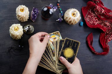 Falcı kadın elleri ve koyu ahşap masa üzerinde tarot kartları. Kehanet kavramı.