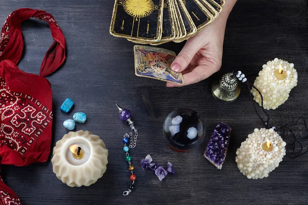 Falcı kadın elleri ve koyu ahşap masa üzerinde tarot kartları. Kehanet kavramı.
