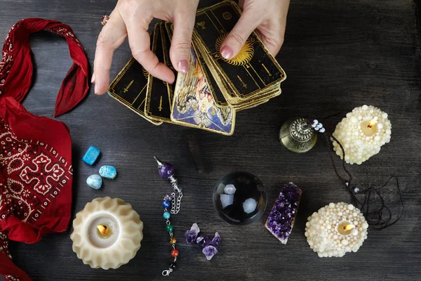 Contador de fortunas mãos femininas e cartas de tarô na mesa de madeira escura. Conceito de adivinhação . — Fotografia de Stock