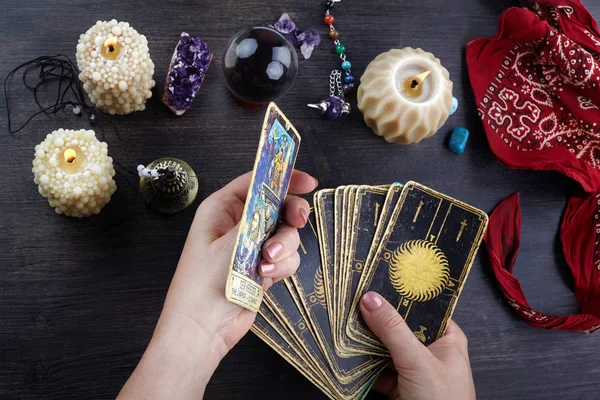 Contador de fortunas mãos femininas e cartas de tarô na mesa de madeira escura. Conceito de adivinhação . — Fotografia de Stock