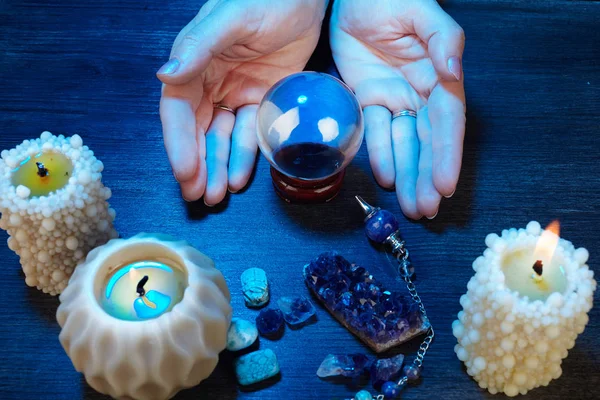 Hände einer Wahrsagerin, die mit einer Kristallkugel im blauen Licht arbeitet — Stockfoto