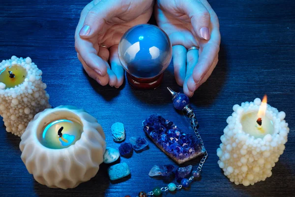 Handen van een Fortune-teller werken met een kristallen bol in blauw licht — Stockfoto