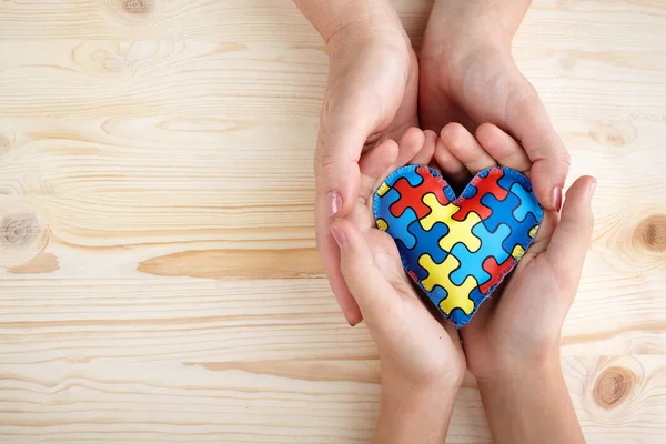 Ziua Mondială de Conștientizare a Autismului, puzzle sau model jigsaw pe inimă cu copii autiști și mâini de femei — Fotografie, imagine de stoc