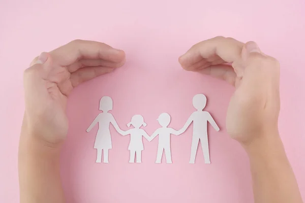 ピンクの背景に家族のペーパーカットを保護する子供の手の高角度ビュー — ストック写真