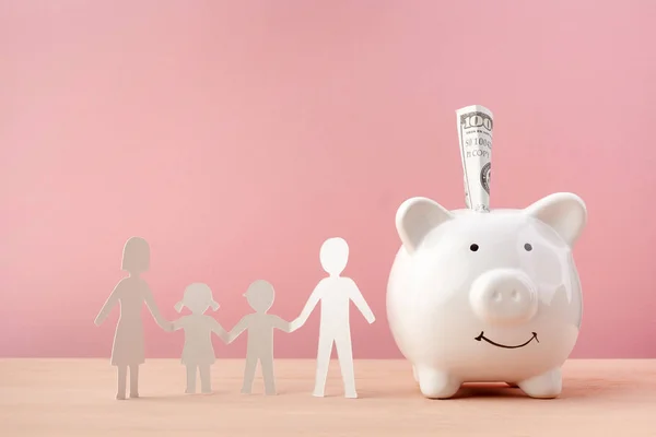 Family Saving Concept With Piggy bank And Family Paper Cut on Pink Background