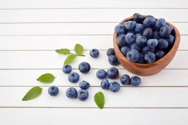 Fresh raw blueberries with leaves on white wooden background. Organic food — Stock Photo, Image