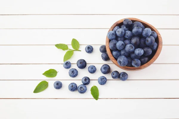 Arándanos frescos crudos con hojas sobre fondo de madera blanca. Alimentos ecológicos — Foto de Stock