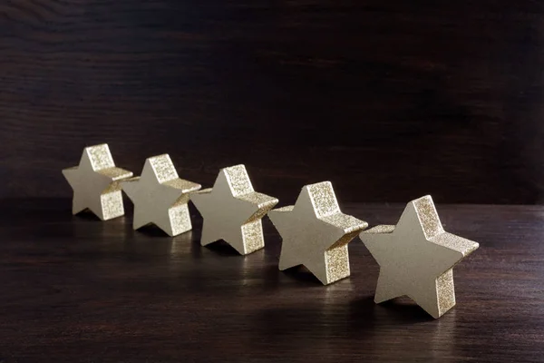 Cinque stelle d'oro su sfondo di legno scuro, concetto top rating — Foto Stock