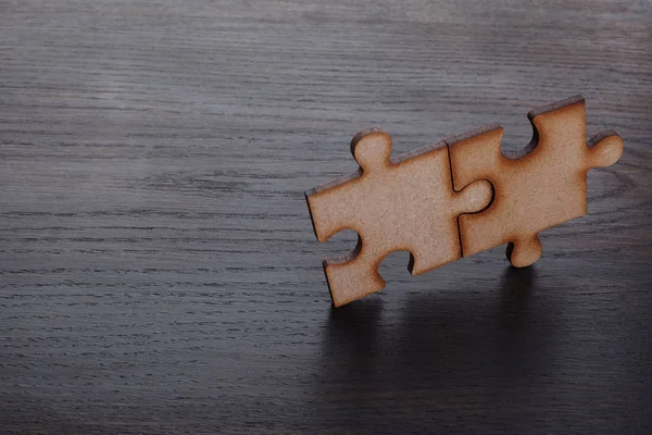 Two Wooden pieces of jigsaw puzzle on wooden background